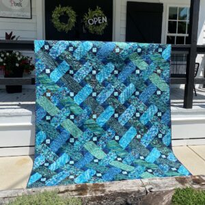 Ribbon Weave quilt hung over the railing of a quilt shop