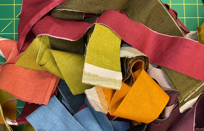 A variety of narrow fabric strips in a pile.