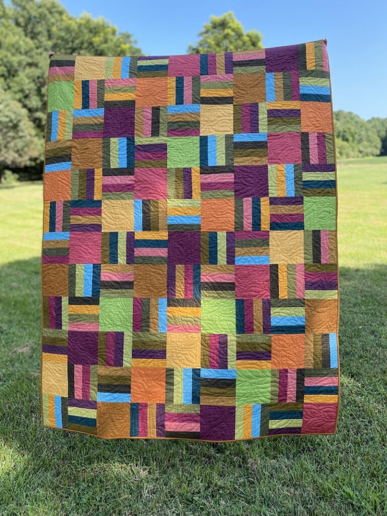 Lap quilt made from squares in fall colors.