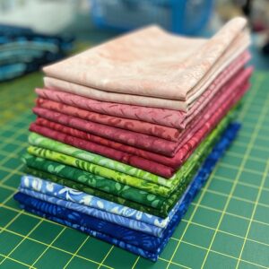 stack of folded fabric in pinks, greens, and blues