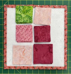 Squares of fabric in green and three shades of pink.