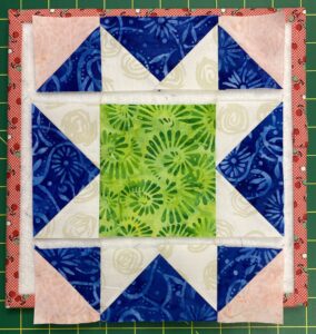 Mosaic Star quilt block in blue, white, pink, and green with the rows of the block sewn together