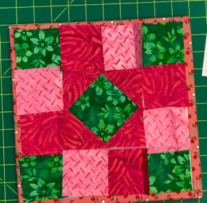 Pieces of a quilt block in pink and green fabrics showing layout of the block