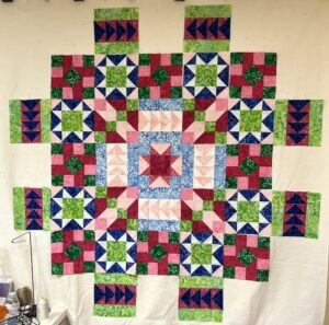 Photo of quilt in progress with the blocks on a design wall