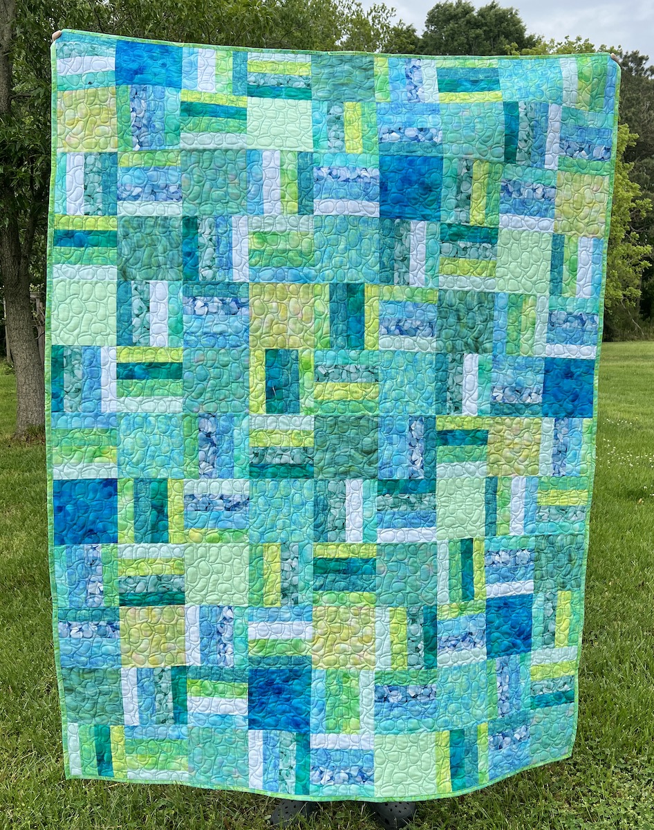 Quilt in sea glass colors - blues and greens, made from squares and fabric strip sets.